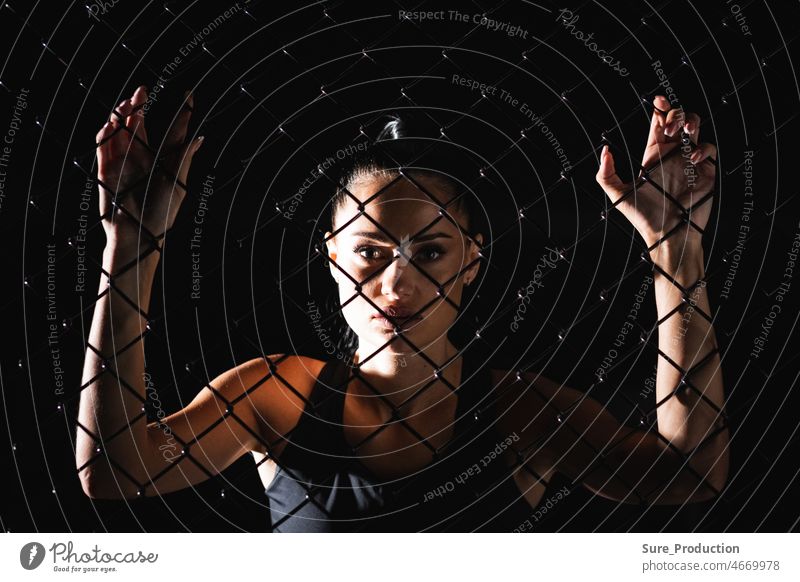 The idea of overcoming psychological and physical barriers and obstacles Young athletic woman looks at you through the mesh adult female hand person beautiful
