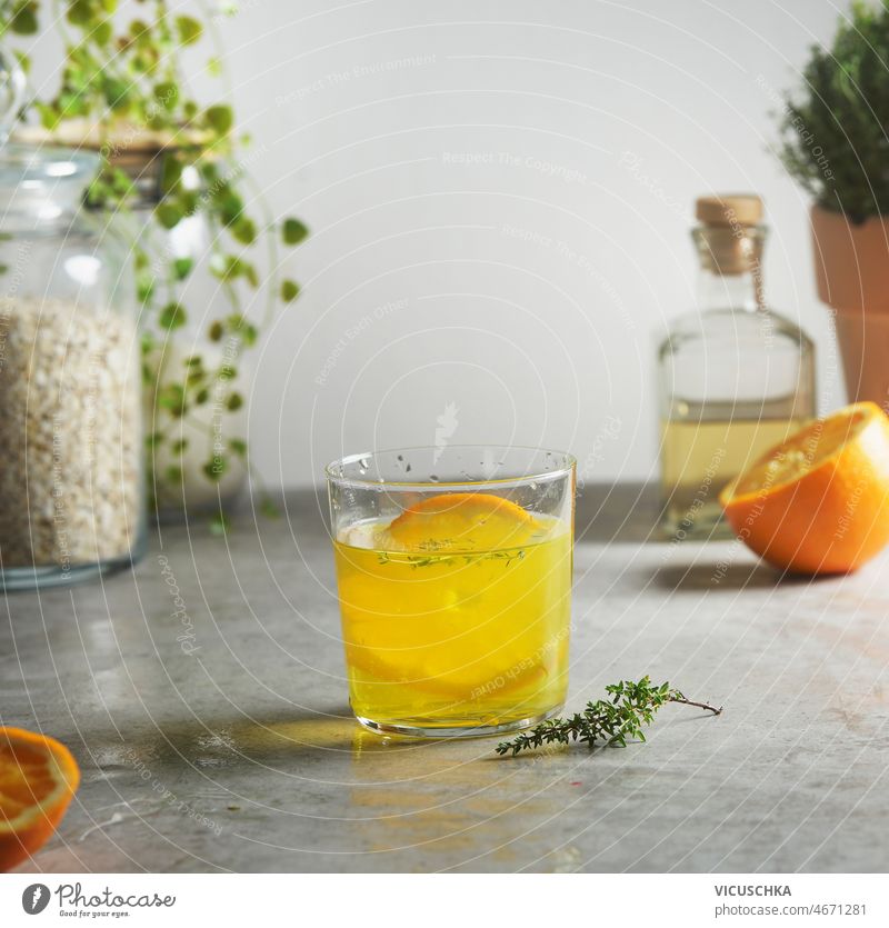 Homemade orange lemonade with thyme at grey concrete kitchen table homemade half glass jar oats bottle preparing refreshing summer drink front view beverage