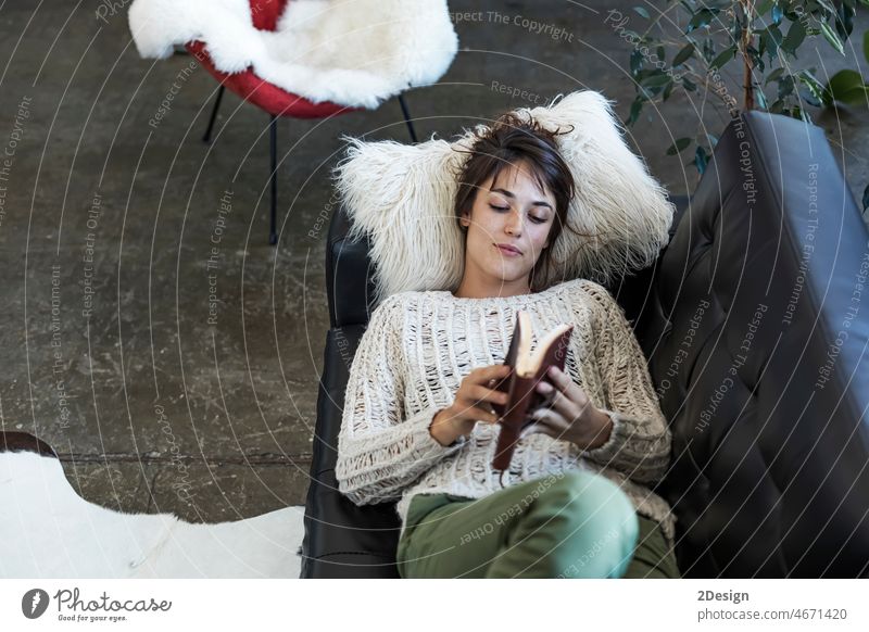 Woman lying on a sofa and reading a book woman indoor resting female relaxation leisure couch leather caucasian smiling living room pillow happiness happy