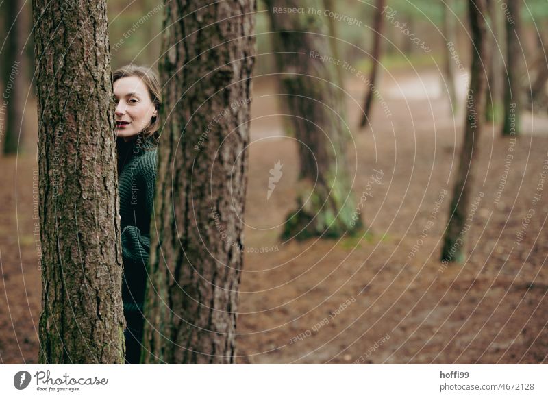 a woman, hidden by trees, looks confidently into the camera Looking into the camera portrait Pensive Eyes Experiencing nature Actress Tree trunk