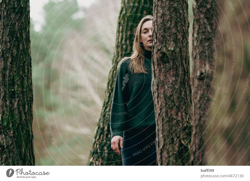 a woman behind trees looks thoughtfully into the camera Looking Young woman melancholically portrait Pensive Calm Meditative Forest Strand of hair Nature