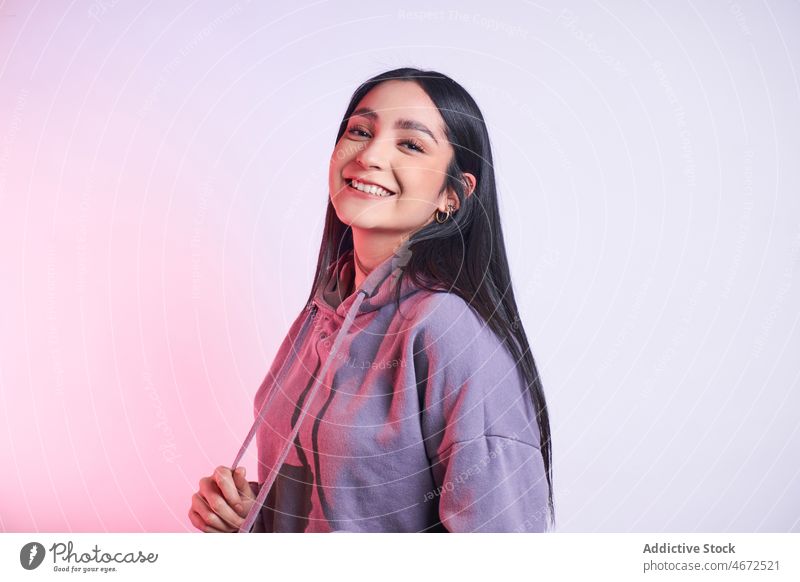 Positive woman in casual outfit portrait smile appearance positive hoodie cheerful happy glad young trendy optimist long hair attire joy content studio delight