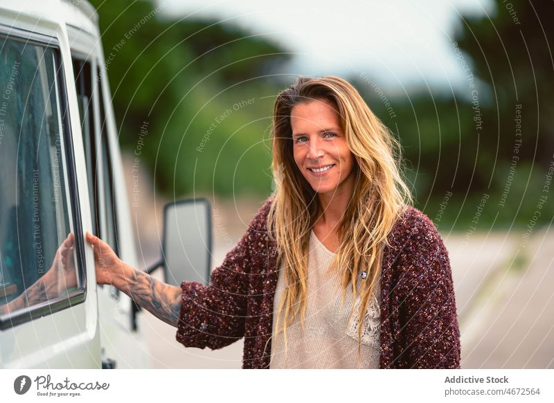 Smiling woman standing near motorhome during road trip traveler van wanderlust explore caravan female camper rv door journey transport adventure vacation nature