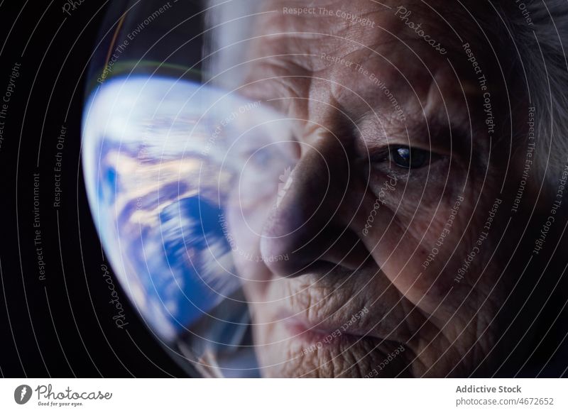 Senior woman in spacesuit looking at Earth globe earth think future pensive planet serious thoughtful focus senior concentrate concept search inspiration