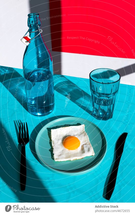 Plate with fried egg and tableware and bottle with glass nutrition delicious plate fork tasty knife water food serve meal fresh yummy cuisine drink summer