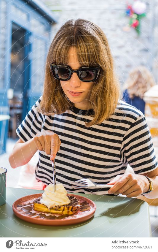Cheerful woman eating dessert on terrace of cafe waffle ice cream sweet gourmet treat delicious tasty food flavor palatable fresh product female serve france
