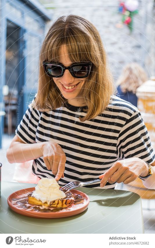Cheerful woman eating dessert on terrace of cafe waffle ice cream sweet gourmet treat delicious tasty food flavor palatable fresh product female serve france