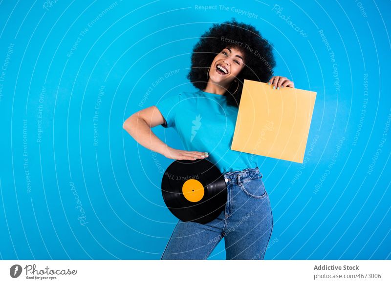 Positive Hispanic woman with vintage vinyl record afro retro smile nostalgia old fashioned meloman ethnic happy packaging style appearance hairstyle feminine