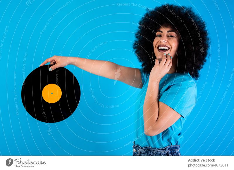 Positive Hispanic woman with vintage vinyl record afro retro smile nostalgia old fashioned meloman ethnic happy style appearance hairstyle feminine casual