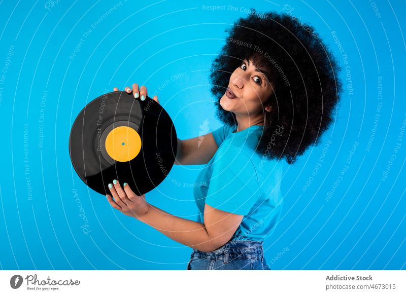 Positive Hispanic woman with vintage vinyl record afro retro smile nostalgia old fashioned meloman ethnic happy style appearance hairstyle feminine casual