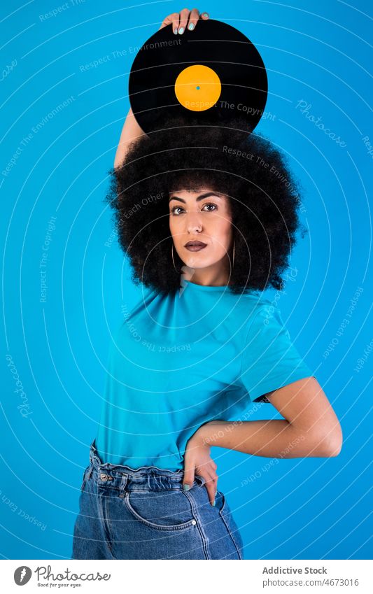 Hispanic woman with vinyl record on head afro retro vintage nostalgia old fashioned meloman style appearance hairstyle feminine casual attractive charming