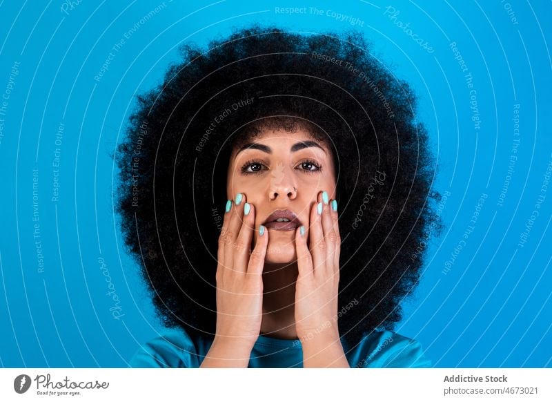 Hispanic woman with Afro hairstyle afro fashion trendy appearance feminine touch cheek attractive charming studio model female hispanic gorgeous beautiful