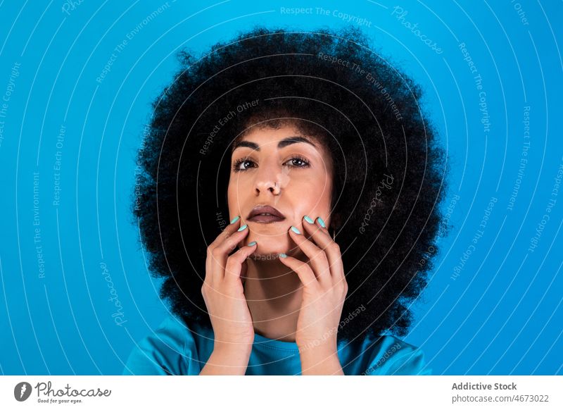Hispanic woman with Afro hairstyle afro fashion trendy appearance feminine touch cheek attractive charming studio model female hispanic gorgeous beautiful