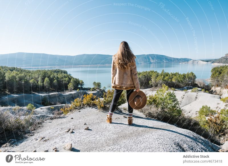 Woman standing on boulder and admiring nature woman lake admire scenery shore rock freedom contemplate environment female mountain highland outerwear
