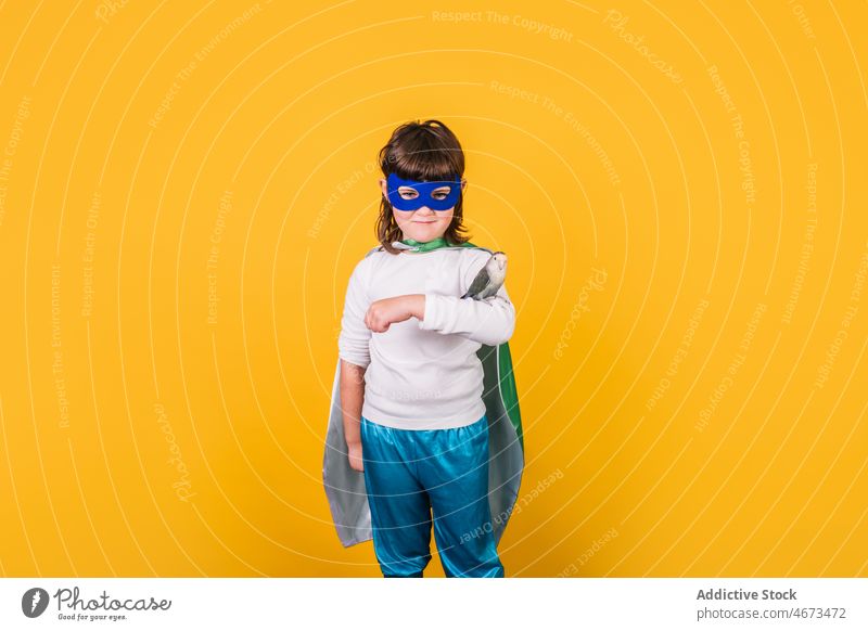 Smiling kid in superhero clothes with parrot girl child bird costume studio brave courage portrait pet power ambition mask individuality demonstrate owner cape