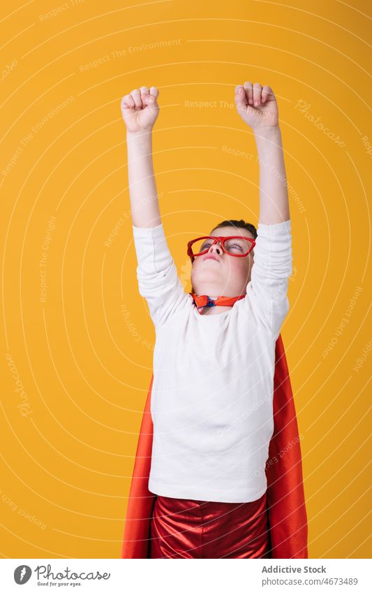 Kid in superhero outfit raising arms up boy child flight fly clench fist costume portrait studio arms raised power kid courage confident cape brave strong