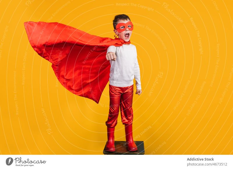 Boy in superhero uniform pretending to fly boy child mask flight clench fist costume portrait studio power kid courage confident cape brave strong personality
