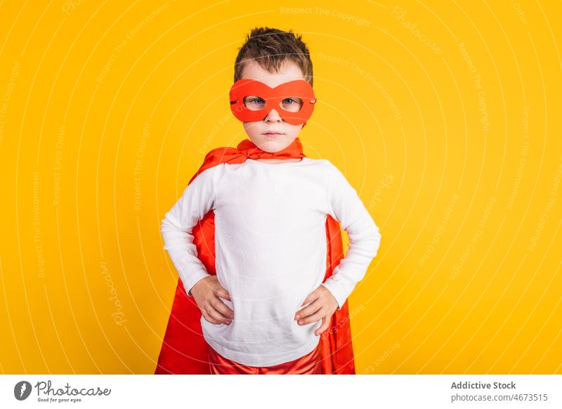Confident superhero child thinking in studio boy costume courage brave power ambition portrait mask hand on waist kid confident cape champion strong personality