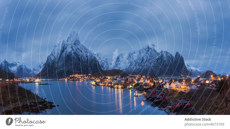 Amazing view of snowy mountains and village located at bottom range settlement house sunset highland landscape picturesque lofoten island norway reine hill