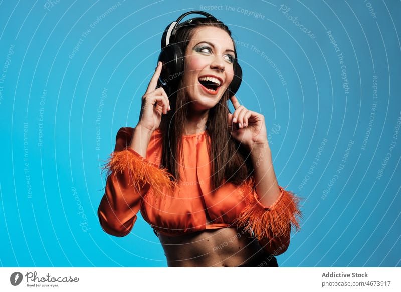 Smiling woman in headphones singing in studio song music vocalist smile cheerful hobby makeup playlist sound style fashion design trendy appearance happy