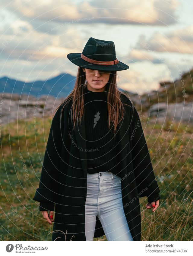 Peaceful woman in hat on meadow peaceful tranquil style nature harmony trip tourism female trendy fashion outerwear garment feminine eyes closed lady tourist