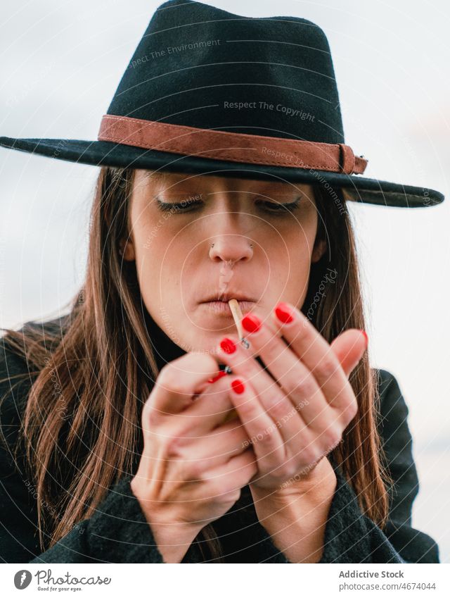 Woman in hat lighting cigarette woman smoke smoker habit street style nicotine tobacco addict joint female lady town appearance unhealthy attractive glad wear