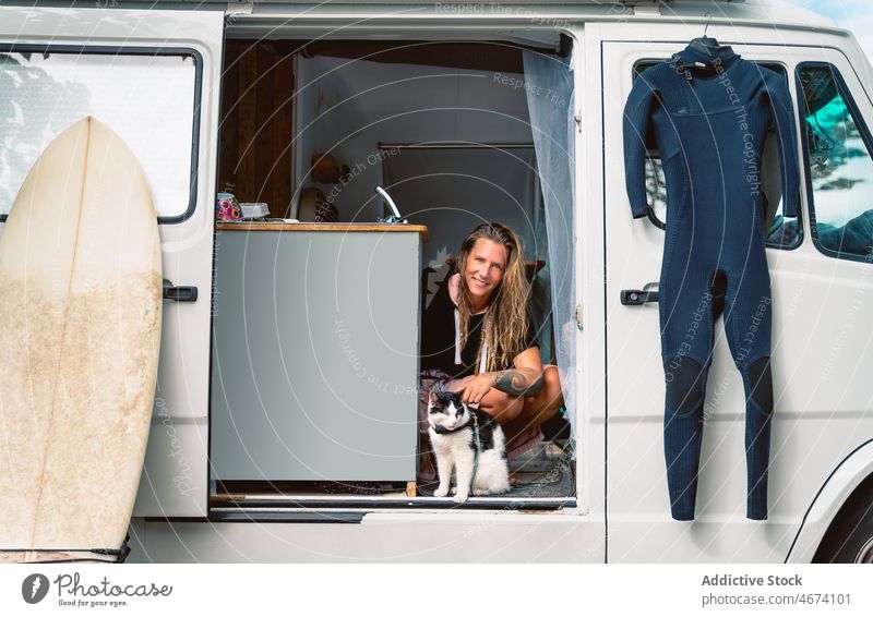 Cheerful surfer with cat in traveling van woman trailer smile surfboard camper cheerful together female pet summer hobby positive water sports holiday vacation