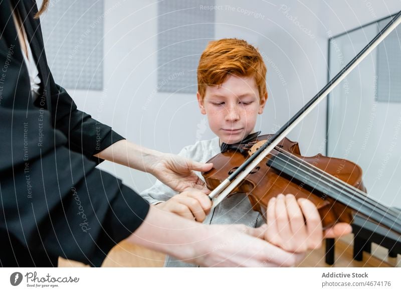 Boy and teacher at violin lesson class boy child bow music school learn professional woman classroom musician sound perform learner redhead ginger classic study