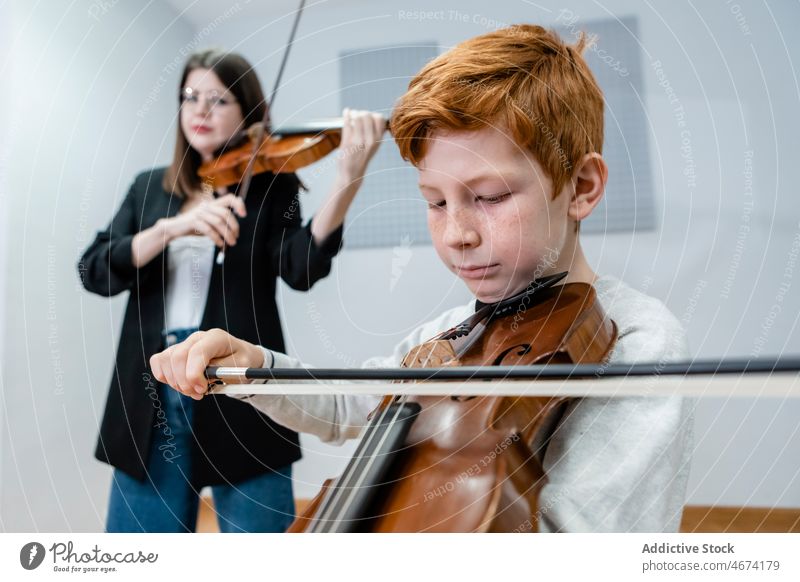 Music teacher and child playing violins together music lesson musician school class boy woman education pupil practice classroom learn bow note kid tutor study