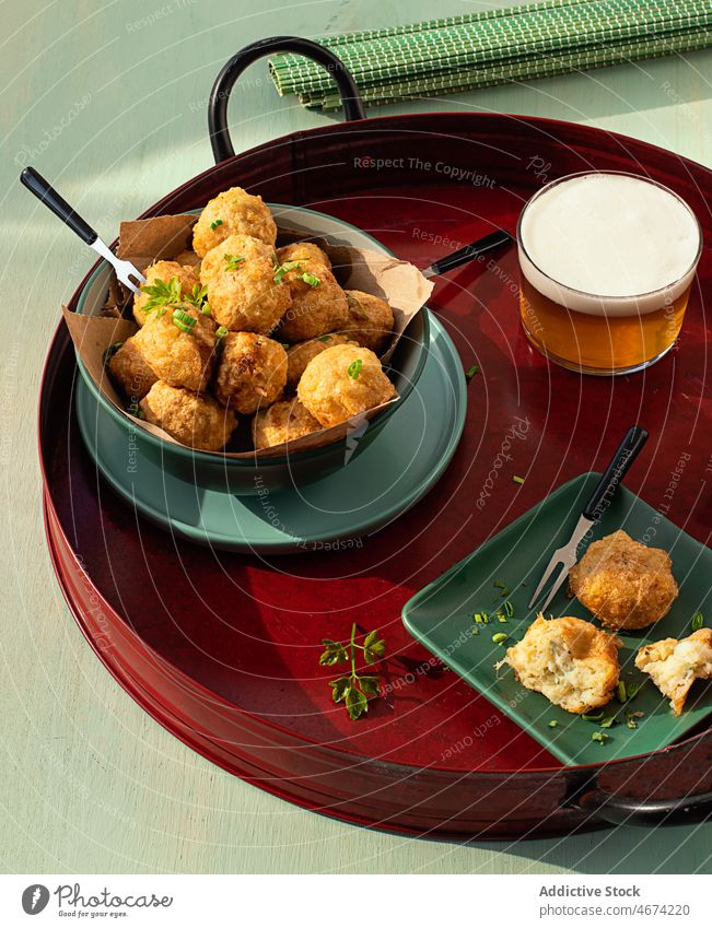 Codfish fritters server on tray with fresh herbs and glass of beer codfish snack balls food parsley fishcake bar deep fried tapas portuguese codfish balls spain