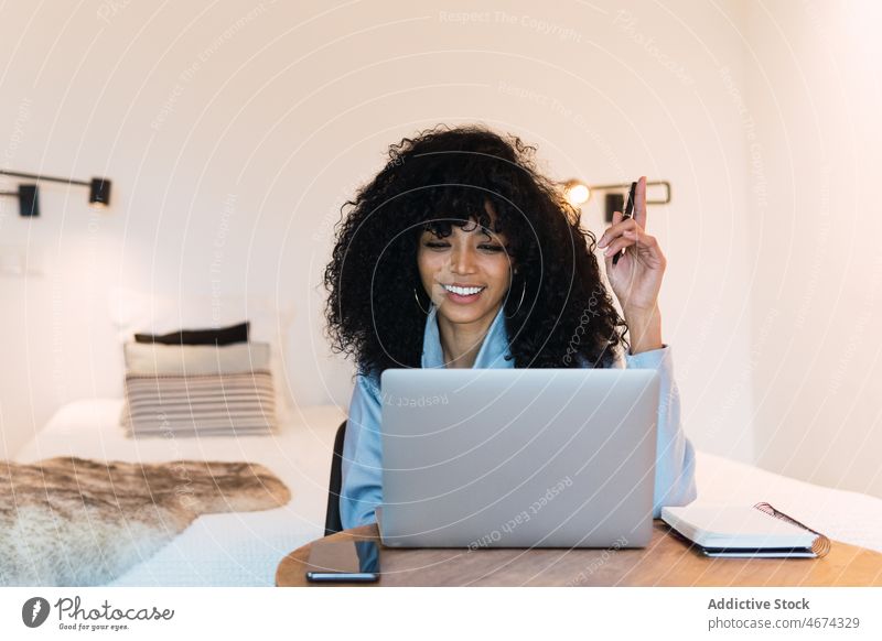 Smiling black woman working on laptop at home using online internet netbook smartphone notebook female african american connection freelance browsing mobile