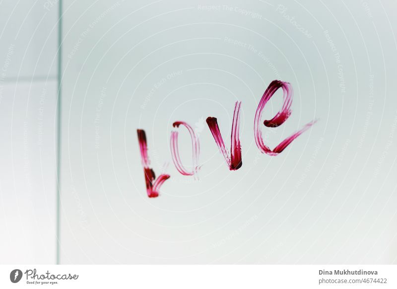 Love word written with red pink lipstick on a mirror of a bathroom. Romantic surprise love message on a glass mirror surface. Words and phrases. symbol