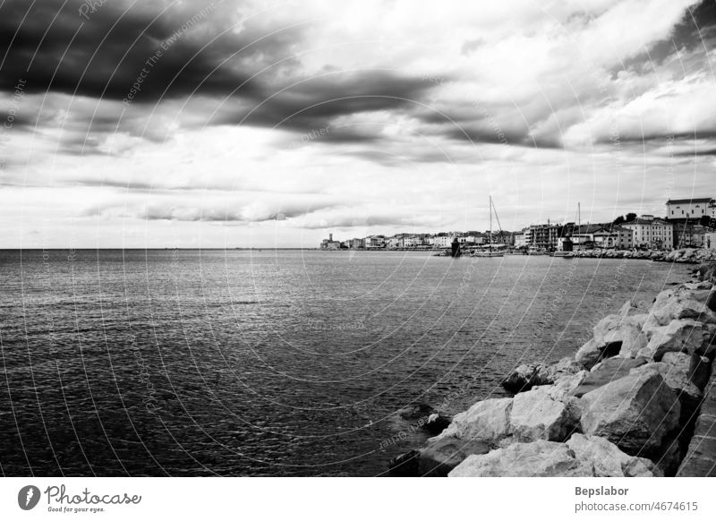Black and white view of the Piran coast under a cloudy sky adriatic europe harbour house lighthouse mediterranean pier piran port sea slovenia town water