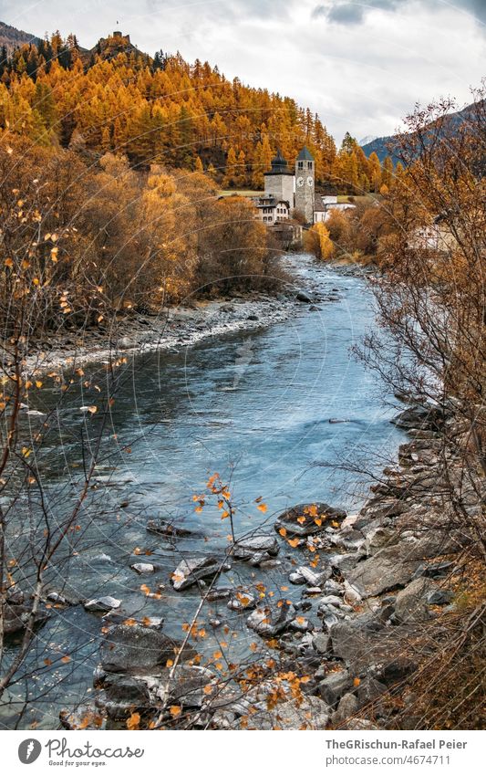 River in front of church in autumn - Engadin Engadine Water trees skylarks Switzerland TOURISM Landscape Mountain Exterior shot Colour photo Tree