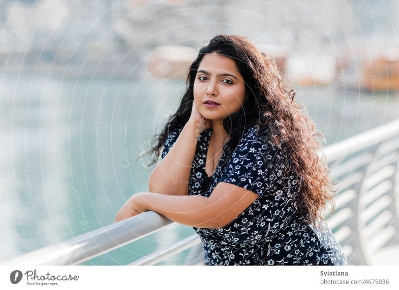 Portrait of a beautiful Indian girl standing at the parapet on the embankment. woman asian promenade walking street positive emotion indian ethnicity outdoor
