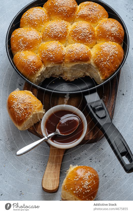 Pull apart rolls in frying pan pull apart bakery bread bun sauce sesame pastry homemade baked fresh sweet food cutting board seed delicious tasty serve yummy
