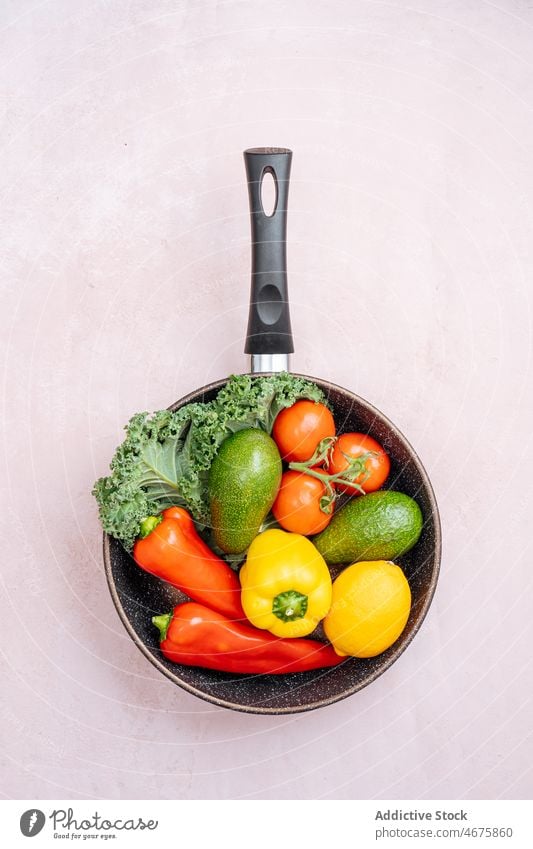 Frying pan with assorted raw vegetables frying pan healthy food pepper avocado tomato greens organic vitamin ingredient ripe fresh kitchen natural recipe