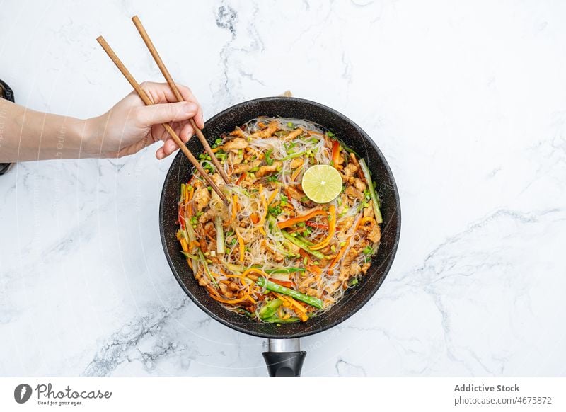 Anonymous person eating stir fry rice noodles with vegetables chopstick meal culinary cuisine food delicious tasty dish hungry appetite dinner yummy gastronomy