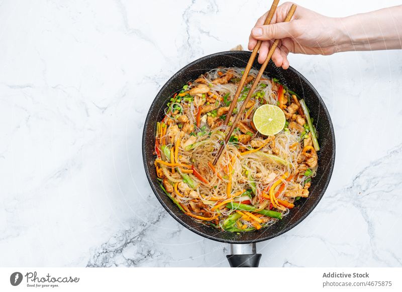 Anonymous person eating stir fry rice noodles with vegetables chopstick meal culinary cuisine food delicious tasty dish hungry appetite dinner yummy gastronomy