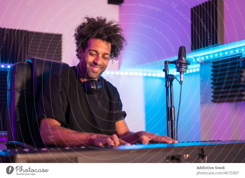 Black man playing piano in modern recording studio musician smile happy song talent melody male ethnic black focus african american neon rehearsal sound
