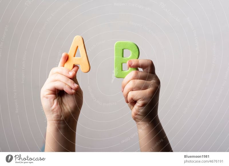 Hands holding two spongy alphabet AB letters backdrop isolated background block capital case collaboration beside concept level mix order word hand kid creative