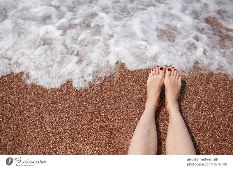 Travel concept - Woman's legs on beautiful tropical beach with pebble sand. Feet on sand and wave in summer time. girl barefoot in ocean water on vacation travel. Feel happy and relax. copy space.
