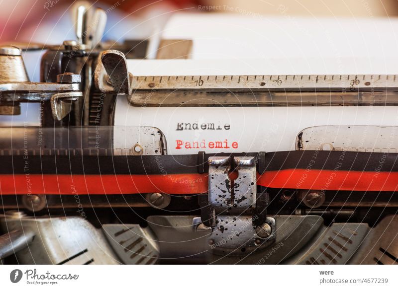 The German word Endemie Pandemie written with an old mechanical typewriter with red and black ribbon in black and red color on a white sheet of paper Covid