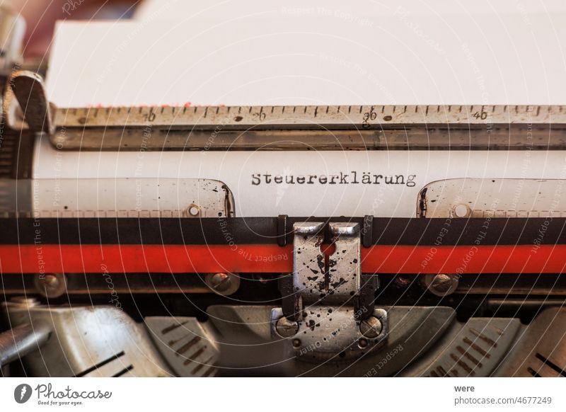 The German word Steuererklärung written with an old mechanical typewriter with red and black ribbon in black ink on a white sheet of paper Stop tax Typewriter