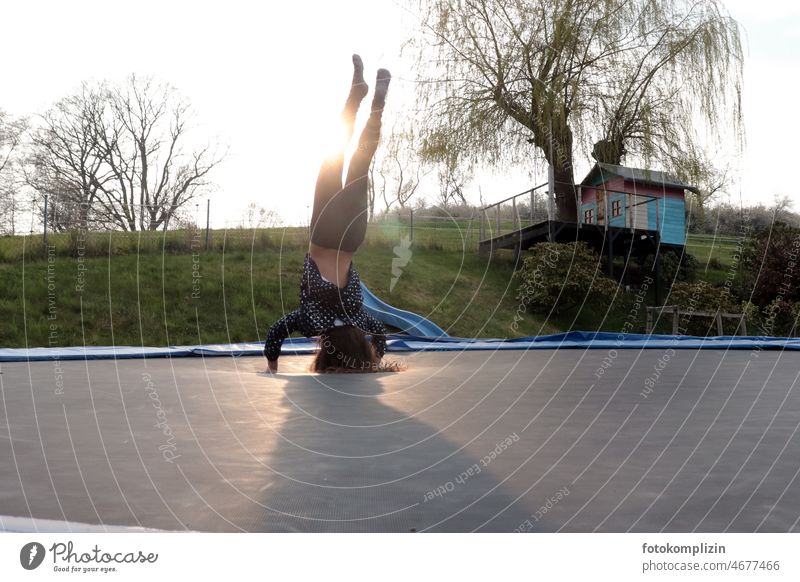Beginning of spring: girl doing headstand on trampoline with tree house in background Child Go crazy Tree house Trampoline Playing move be happy by oneself