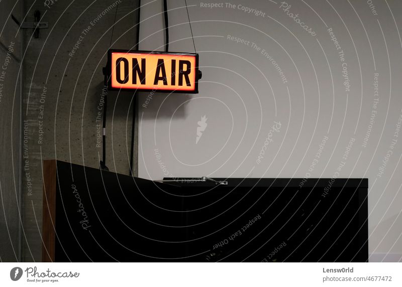 Glowing "On Air" sign over a door leading to TV studio broadcast broadcasting communication concept glowing light live livestream media on air on air sign
