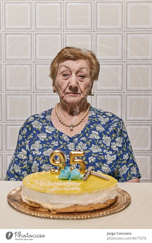 An elderly womanlooking at a cake topped with candles. one retirement casual mature wrinkled positive mood love cheerful female happiness people family