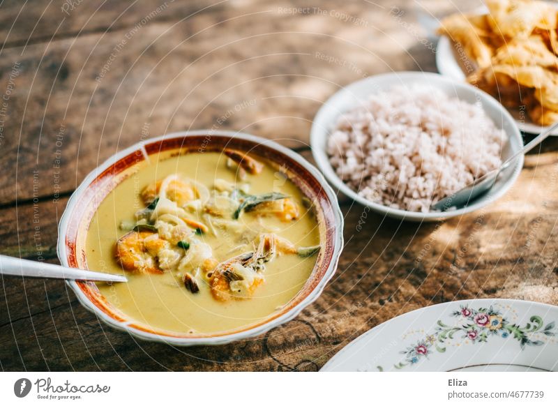 Yellow shrimp curry with rice and Sri Lankan papadams on a wooden table Curry powder Shrimps Rice Papadams Eating Delicious tart Wooden table bowl Meal Asian