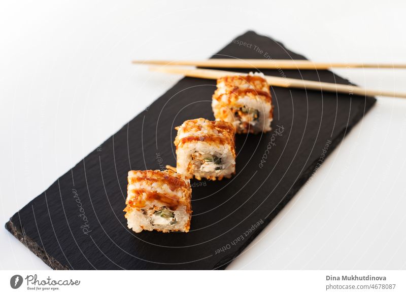 Sushi japan food on black stone plate at sushi restaurant or takeout with chopsticks on white. Gourmet delicious sushi japanese food with chopsticks fresh at the restaurant or takeout delivery.
