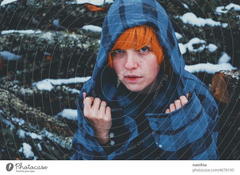 Redhead androgynous model in a winter scene people teen androgynious queer non-binary young youth cold hood hoodie redhead warm warmth thinkg alone wood